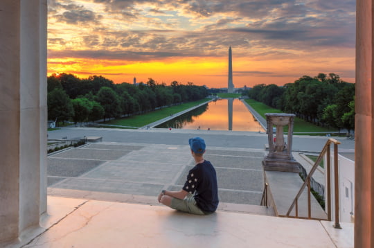 A teen watches the sunset over the Washington Monument in Washington DC